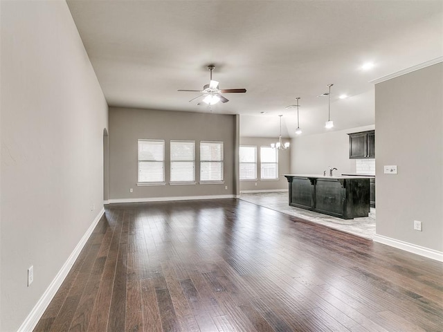 unfurnished living room featuring dark hardwood / wood-style floors, sink, and ceiling fan with notable chandelier