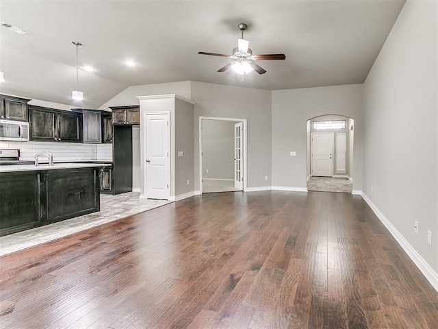 unfurnished living room with lofted ceiling, ceiling fan, sink, and dark hardwood / wood-style floors