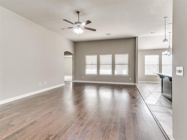 unfurnished living room featuring hardwood / wood-style floors and ceiling fan with notable chandelier