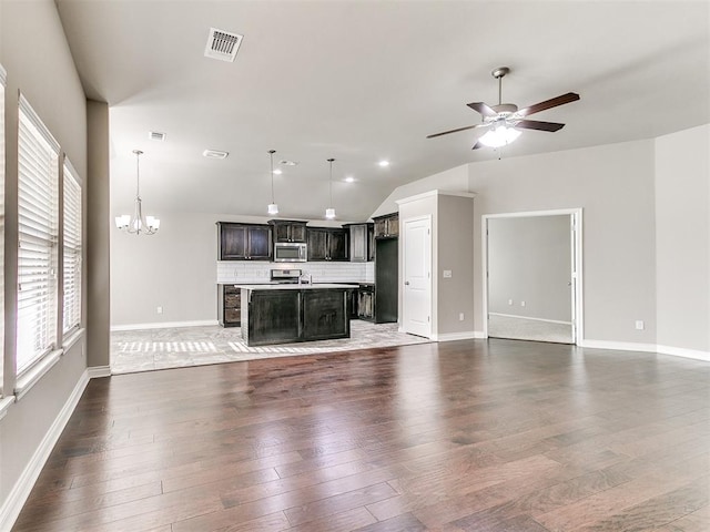 unfurnished living room featuring ceiling fan with notable chandelier, hardwood / wood-style flooring, and vaulted ceiling