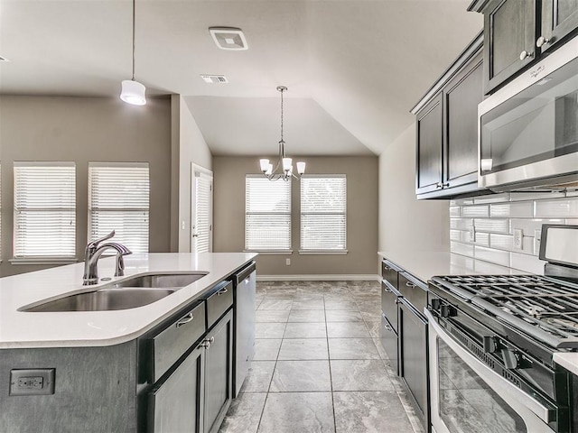 kitchen with an inviting chandelier, sink, vaulted ceiling, an island with sink, and appliances with stainless steel finishes