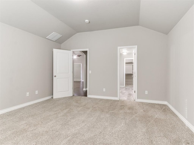 unfurnished bedroom with carpet, lofted ceiling, a spacious closet, and a closet