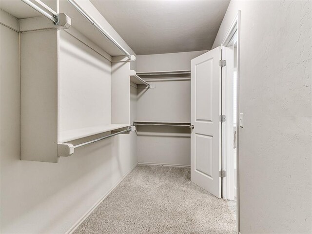 walk in closet featuring light carpet