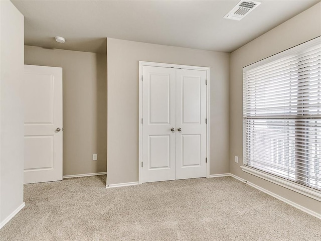 unfurnished bedroom with light carpet, a closet, and multiple windows