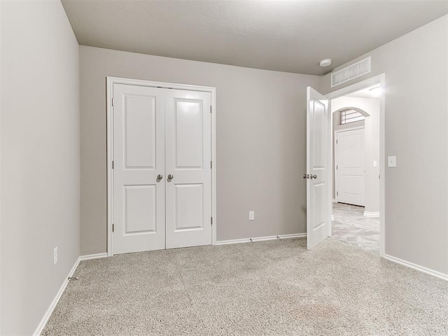 unfurnished bedroom with light colored carpet and a closet