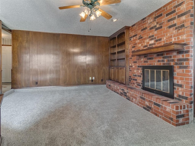 unfurnished living room with carpet, a textured ceiling, and wooden walls