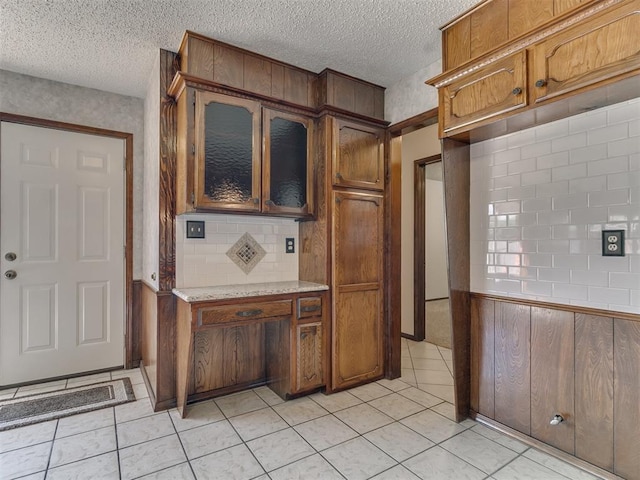 kitchen with backsplash, light tile patterned flooring, and a textured ceiling