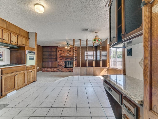 kitchen with a textured ceiling, ceiling fan, light tile patterned floors, oven, and stainless steel gas stovetop