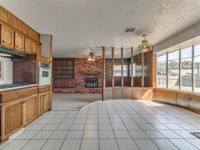 kitchen featuring white oven, light tile patterned flooring, pendant lighting, and a textured ceiling