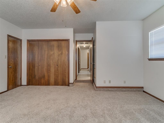 unfurnished bedroom featuring ceiling fan, light colored carpet, and a textured ceiling