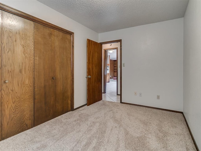 unfurnished bedroom with a textured ceiling, light colored carpet, and a closet