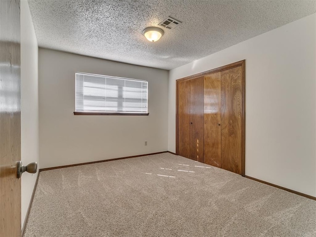 unfurnished bedroom with a textured ceiling, carpet floors, and a closet