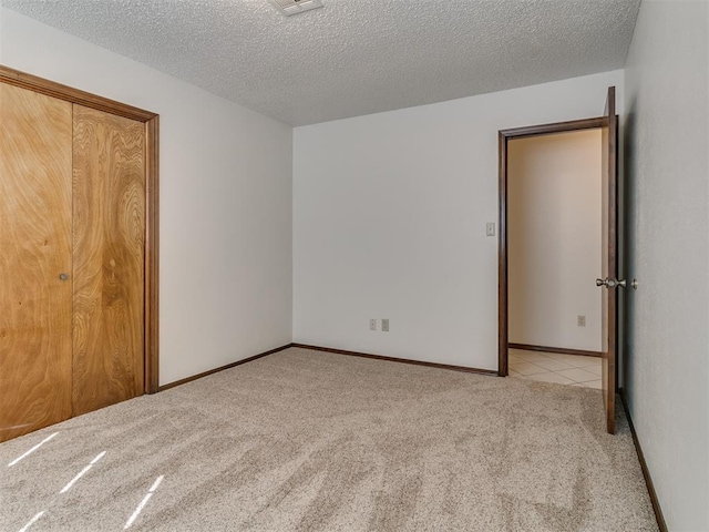 unfurnished bedroom featuring light carpet, a closet, and a textured ceiling