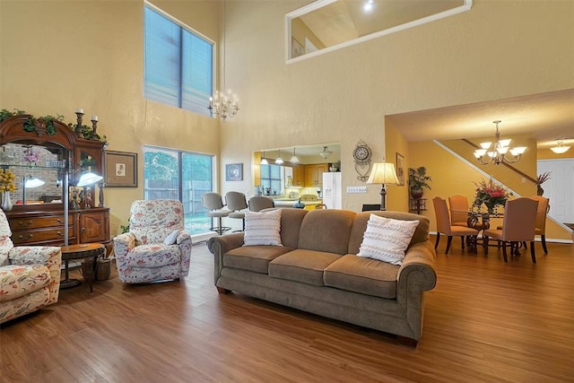 living room featuring wood-type flooring, a high ceiling, and an inviting chandelier