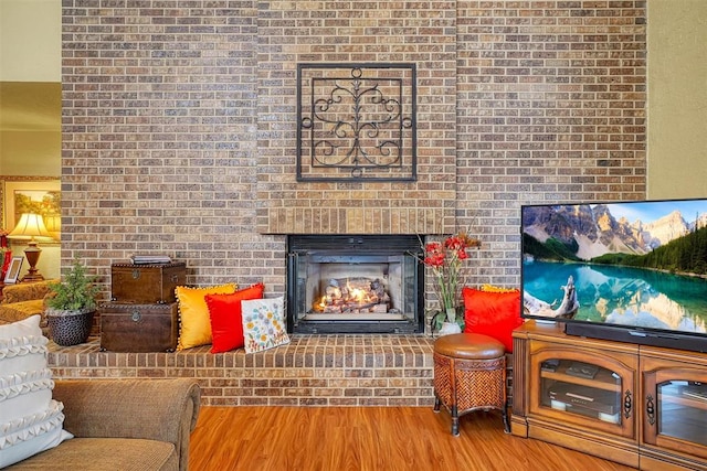 living room with hardwood / wood-style floors, a fireplace, and brick wall