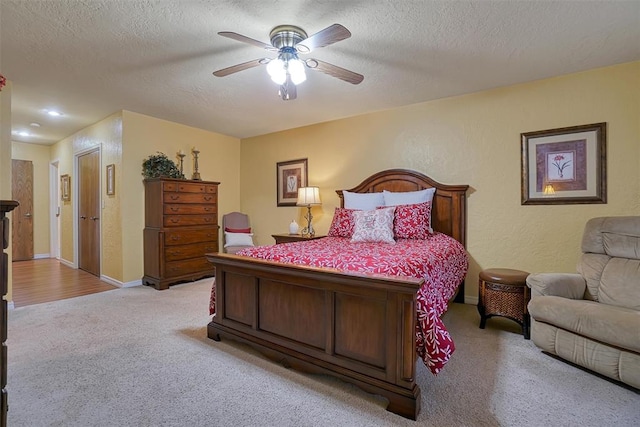 bedroom featuring ceiling fan, light colored carpet, and a textured ceiling