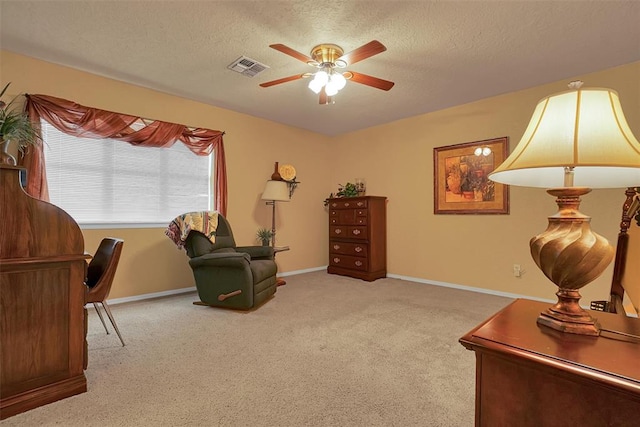 living area with a textured ceiling, light colored carpet, and ceiling fan