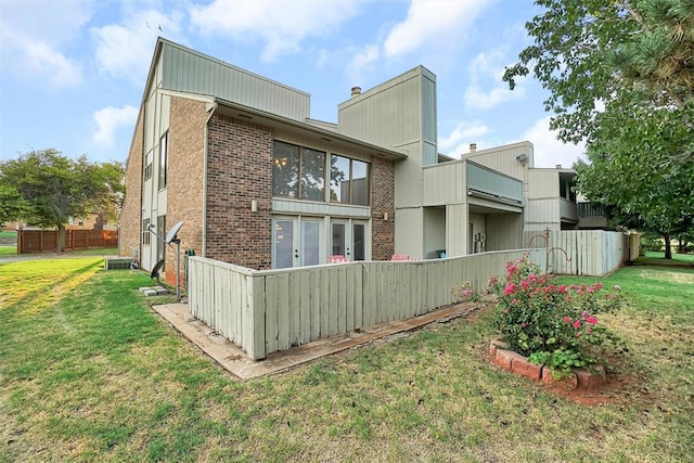 rear view of house featuring a lawn and central AC