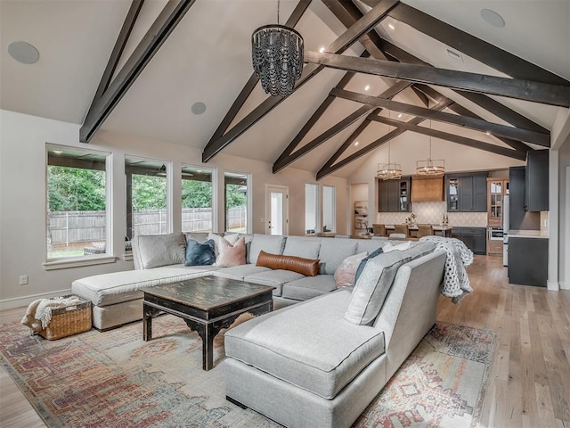 living room with a notable chandelier, beam ceiling, light wood-type flooring, and high vaulted ceiling