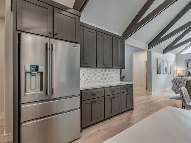 kitchen featuring high end refrigerator, backsplash, lofted ceiling with beams, gray cabinets, and light hardwood / wood-style floors