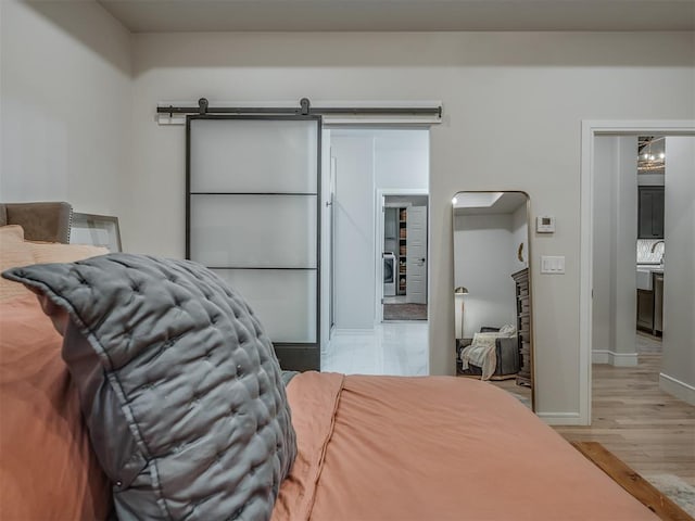 bedroom with a barn door and light hardwood / wood-style flooring