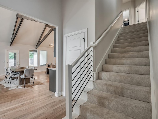 stairs with hardwood / wood-style floors and beam ceiling