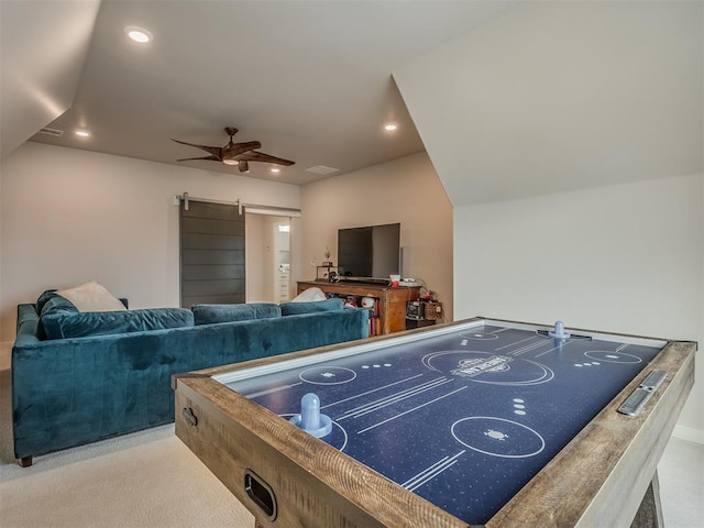 game room with ceiling fan, a barn door, and light carpet