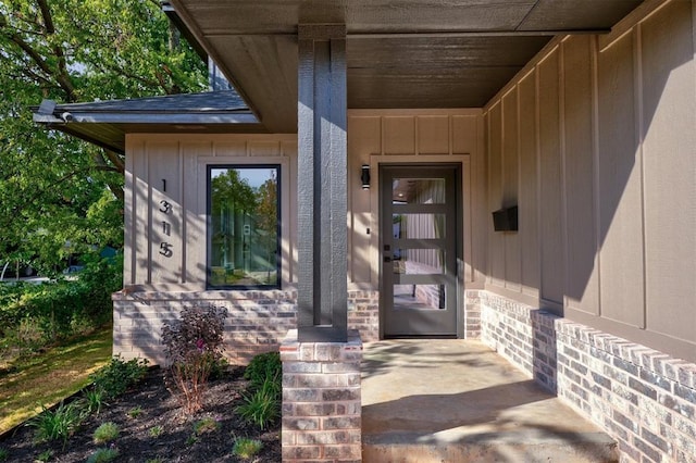 doorway to property featuring brick siding and board and batten siding