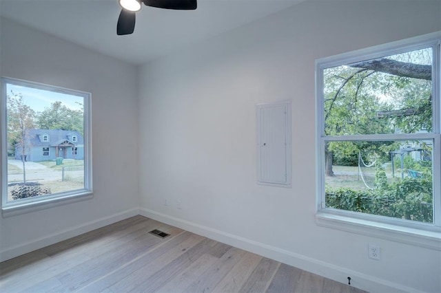 empty room with light wood-style floors, a healthy amount of sunlight, electric panel, and visible vents