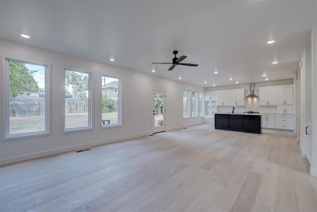 unfurnished living room with light wood-type flooring, a wealth of natural light, and recessed lighting