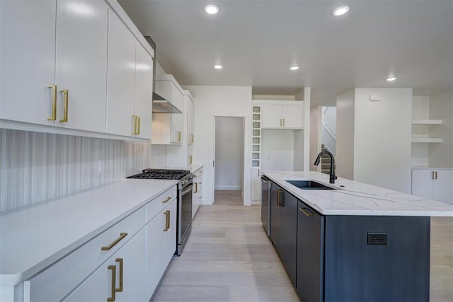 kitchen with appliances with stainless steel finishes, a sink, a center island with sink, and white cabinetry