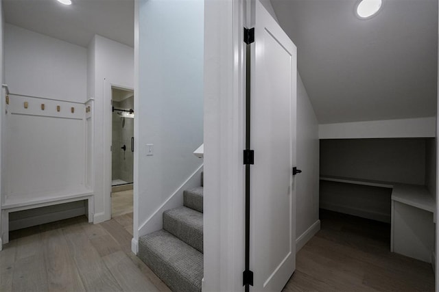 stairway with vaulted ceiling, wood finished floors, and baseboards