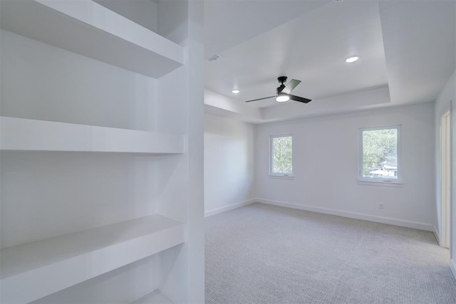 empty room featuring recessed lighting, a raised ceiling, a ceiling fan, light carpet, and baseboards