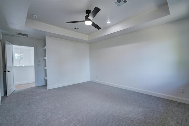 unfurnished room featuring a raised ceiling, visible vents, baseboards, and carpet flooring