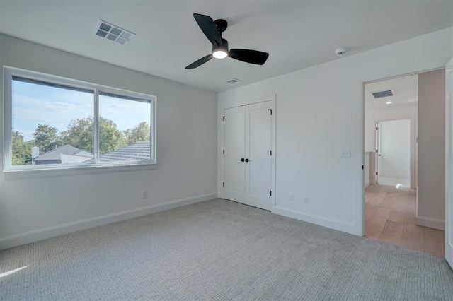 unfurnished bedroom featuring light carpet, baseboards, visible vents, and a closet