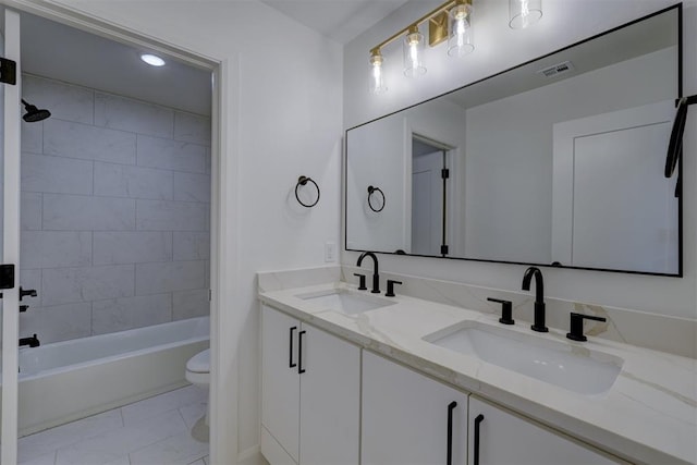 bathroom featuring toilet, double vanity, visible vents, and a sink