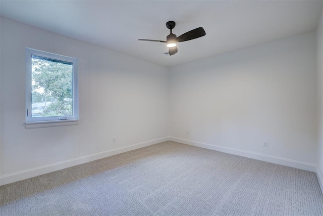 carpeted spare room featuring a ceiling fan and baseboards