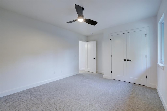 unfurnished bedroom featuring a ceiling fan, a closet, light colored carpet, and baseboards