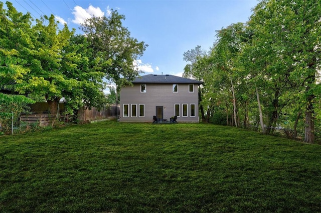 rear view of property with a fenced backyard and a yard