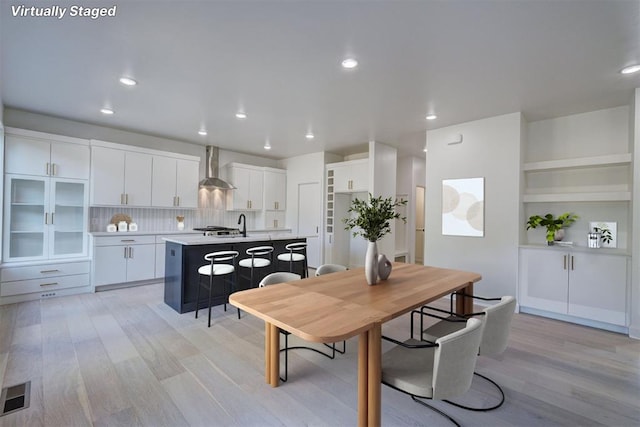 dining area with light wood-style flooring, visible vents, and recessed lighting