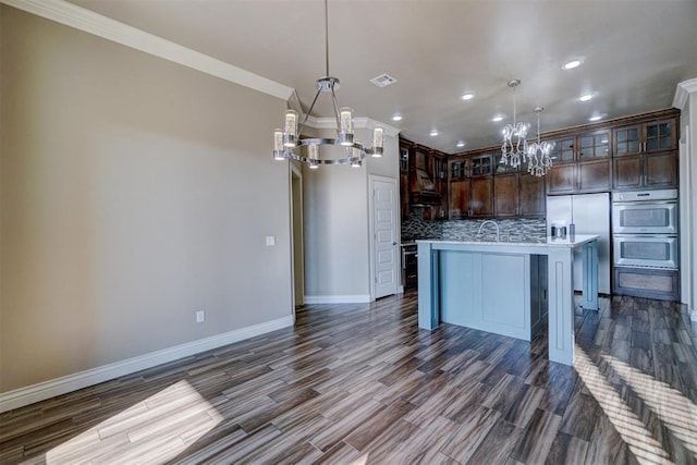 kitchen with pendant lighting, dark hardwood / wood-style flooring, and an island with sink