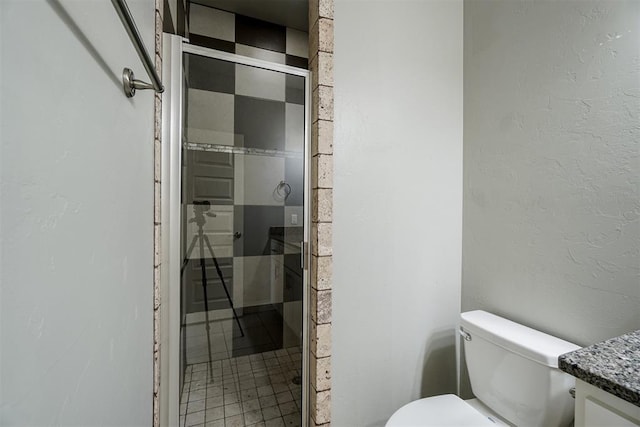 bathroom with tile patterned flooring, vanity, toilet, and a shower with shower door