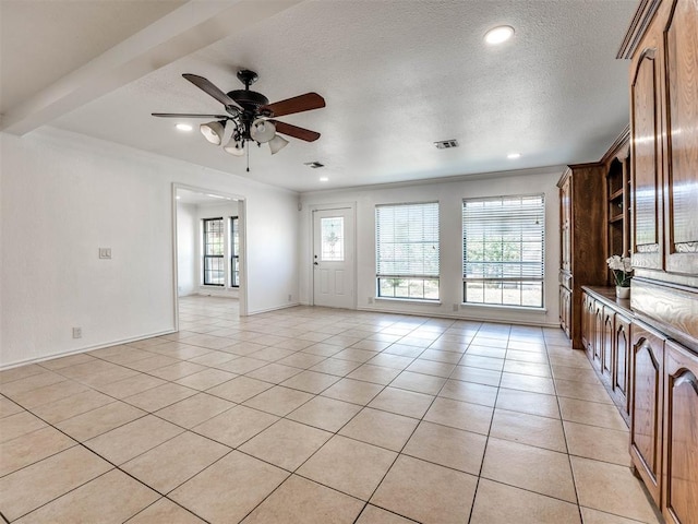 interior space featuring ceiling fan, light tile patterned flooring, ornamental molding, and a textured ceiling