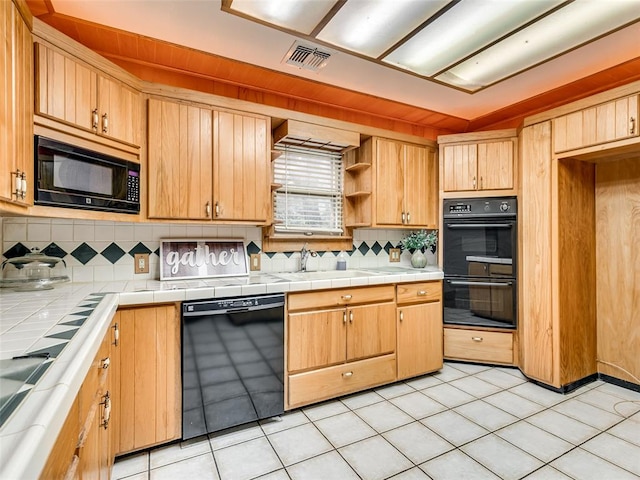 kitchen featuring black appliances, light tile patterned flooring, sink, and tile countertops