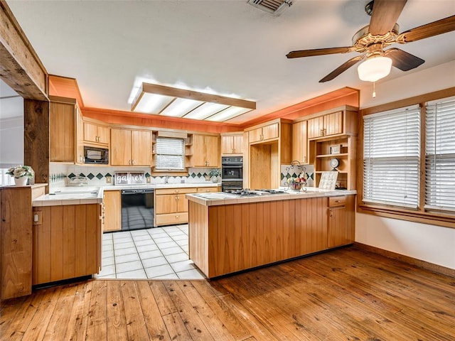 kitchen with ceiling fan, light hardwood / wood-style flooring, kitchen peninsula, decorative backsplash, and black appliances