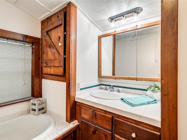 bathroom featuring a bathing tub, vanity, and a textured ceiling