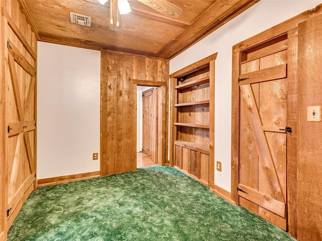 unfurnished bedroom featuring carpet floors, wooden walls, ceiling fan, and wooden ceiling