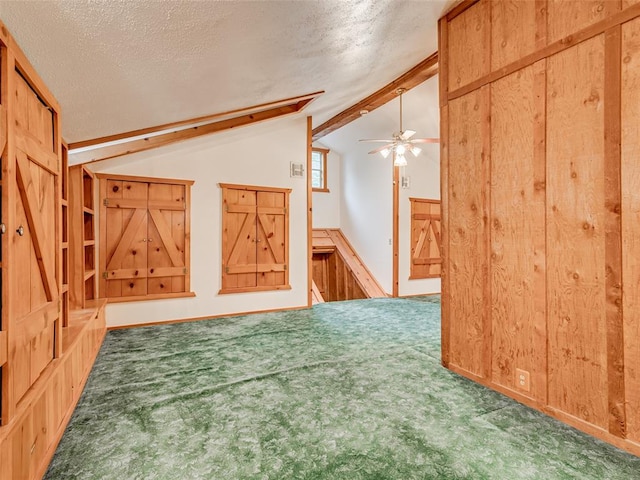 additional living space featuring carpet flooring, vaulted ceiling with beams, wood walls, and a textured ceiling