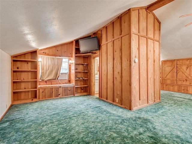 unfurnished living room with carpet, wood walls, vaulted ceiling, ceiling fan, and a textured ceiling