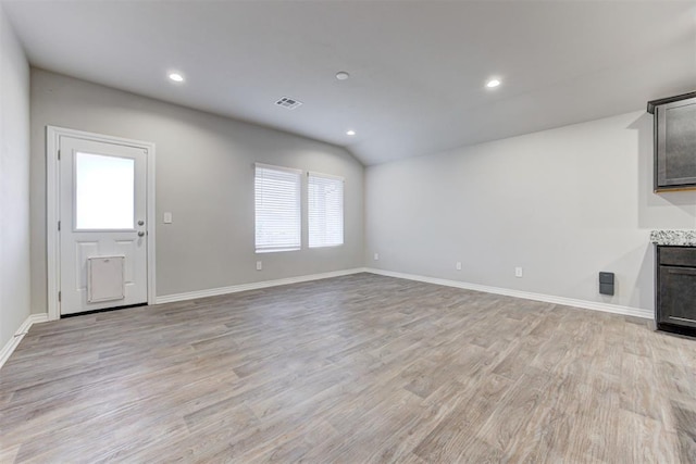 unfurnished living room featuring a wealth of natural light, light hardwood / wood-style floors, and vaulted ceiling